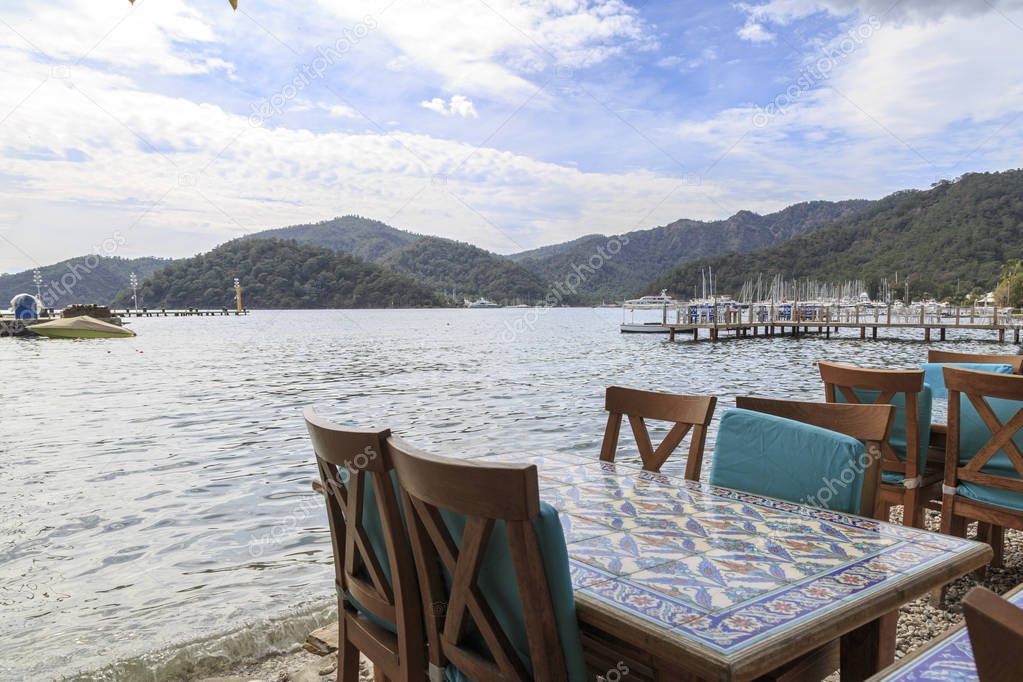 Table with chairs on gocek beach with mountains in gocek, Turkey