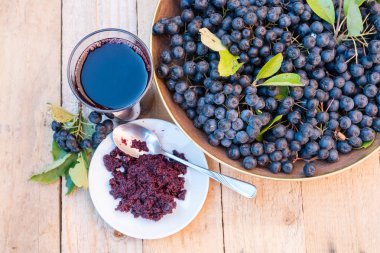 Taze meyve suyu ve olgun siyah chokeberry (Aronia melanocarpa) cam ve berry ahşap zemin üzerine tencerede reçel