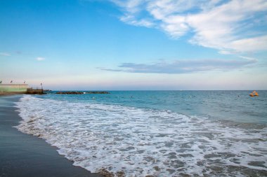 Kumlu bir plaj ve küçük dalgalar ile güzel deniz manzarası. Masmavi deniz suyu. Mavi gökyüzü bulutlu. Plaj. Yaz sezonu. Açık gün. İtalya. San Remo.