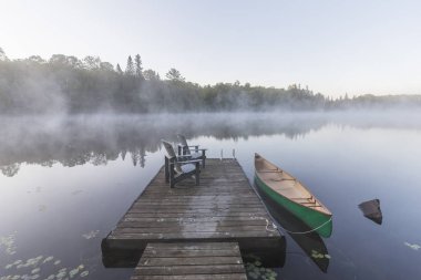 Green canoe and dock on a misty morning - Ontario, Canada clipart