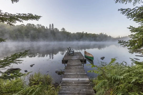 Canoa verde e doca em uma manhã enevoada - Ontário, Canadá — Fotografia de Stock