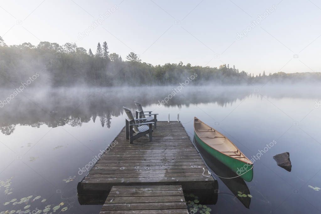 Green canoe and dock on a misty morning - Ontario, Canada