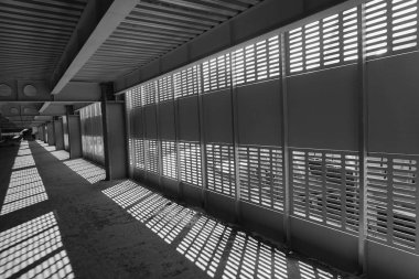 Gölge ve ışık. Siyah ve beyaz. Güneşli gün ışığı terk edilmiş tamamlanmamış shoping alışveriş merkezinde metal kafes üzerinden