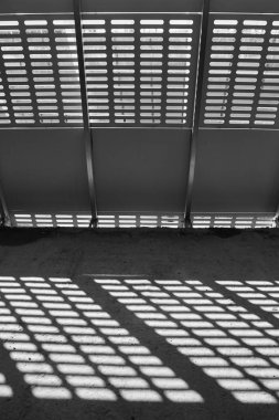 Gölge ve ışık. Siyah ve beyaz. Güneşli gün ışığı terk edilmiş tamamlanmamış shoping alışveriş merkezinde metal kafes üzerinden