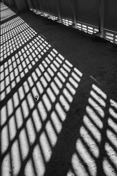 Sombra e luz. Preto e branco. Luz do dia ensolarada da rede de metal no shopping center inacabado abandonado — Fotografia de Stock