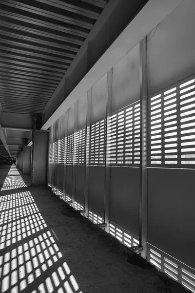 Sombra e luz. Preto e branco. Luz do dia ensolarada da rede de metal no shopping center inacabado abandonado — Fotografia de Stock