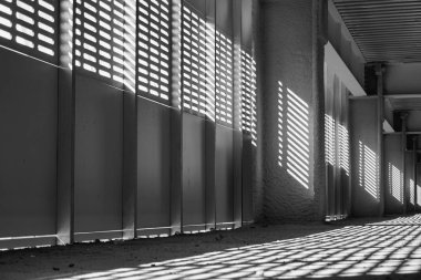 Gölge ve ışık. Siyah ve beyaz. Güneşli gün ışığı terk edilmiş tamamlanmamış shoping alışveriş merkezinde metal kafes üzerinden