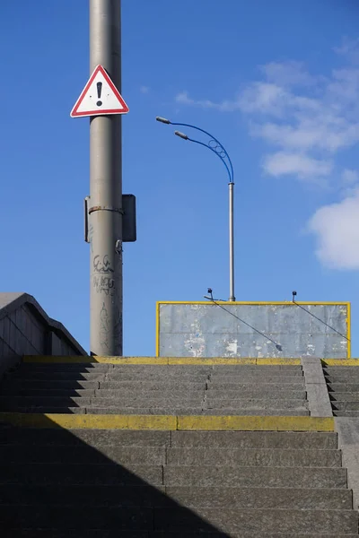 Road znak - czarny wykrzyknik w trójkącie czerwone wiszące na słupie, ostrzeżenie o niebezpieczeństwie. — Zdjęcie stockowe