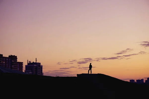 Silhouette Menschen stehen bei Sonnenuntergang auf einem Hügel über der Stadt. — Stockfoto