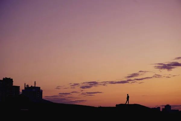 Silhouette Menschen stehen bei Sonnenuntergang auf einem Hügel über der Stadt. — Stockfoto