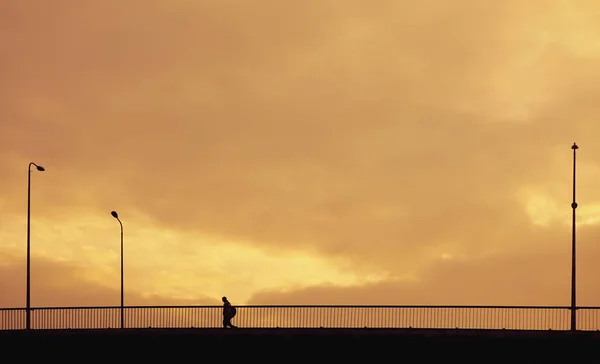 Silhouette person gör på bron vid solnedgången tid i staden. — Stockfoto