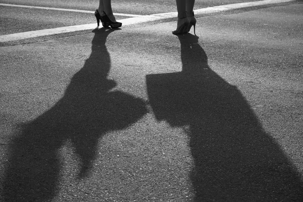 Две современные девушки на высоких каблуках стоят на солнечном асфальте — стоковое фото