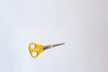 Beyaz arka planda sarı saplı makas.