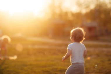 Bulanık bir arka planda küçük bir çocuk altın saatinde açıklıkta