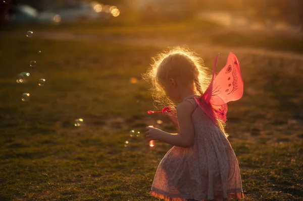 Kleines Mädchen Spielt Mit Seifenblasen Auf Einer Lichtung Bei Sonnenuntergang — Stockfoto