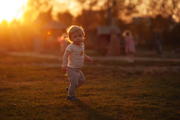 黄昏时分 草地上的小男孩在夕阳西下微笑 — 图库照片