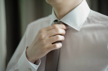 Kravatını bağlayan genç bir adama yaklaş.