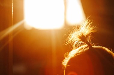 Çocuklar batan güneşin ışınlarında odada oynarlar. Küçük çocuklar evlerinde, arka planda. Çocukların arka planında güneş pencereden parlıyor. Batan güneşin altında evdeki çocukların siluet görüntüleri..