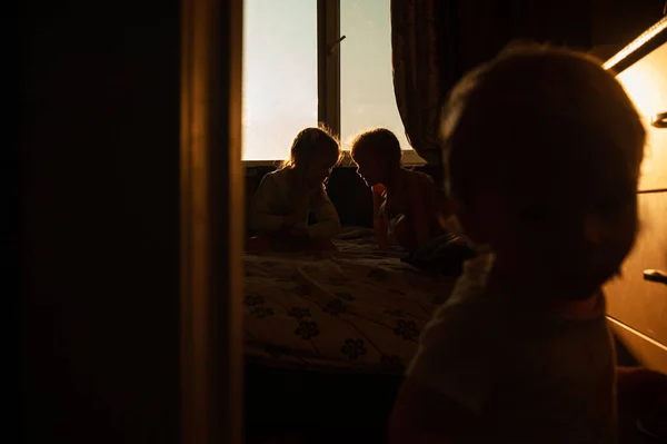 children play in the room in the rays of the setting sun. Little children at home in the backlight. The sun shines through the window on the background of children. Silhouette footage of children at home in the rays of the setting sun.