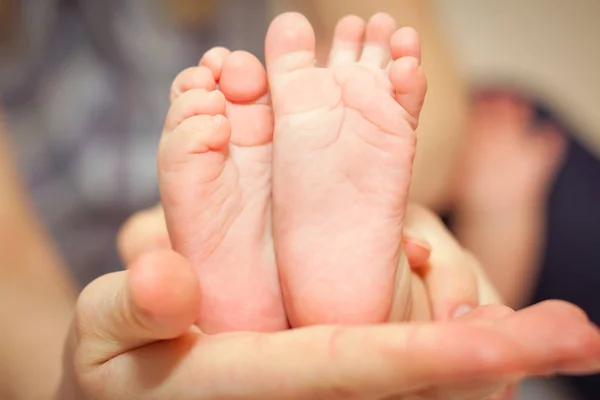 Kis lábak, a baba újszülött, hogy tartsa anya kezét. — Stock Fotó
