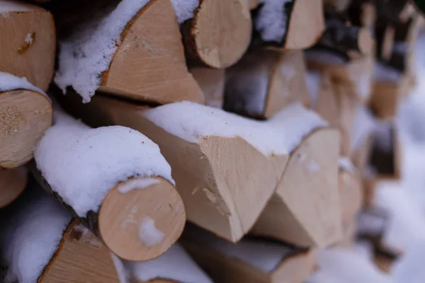 Voetstappen in de sneeuw in de buurt van een stapel brandhout — Stockfoto