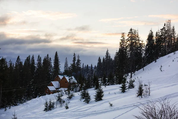 La cabaña del forestal en el bosque nevado de montaña. Colorido amanecer de invierno en los Cárpatos, Feliz Año Nuevo concepto de celebración. Estilo artístico foto post procesado . — Foto de Stock