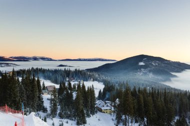 Güneş ışığı tarafından parlak fantastik turuncu akşam manzara. Karlı ağaçları ile dramatik kış sahne. Karpatlar, Ukrayna, Avrupa. Mutlu Noeller