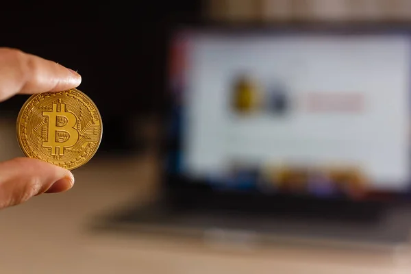 Bitcoin moeda de ouro na mão do homem no fundo do la — Fotografia de Stock