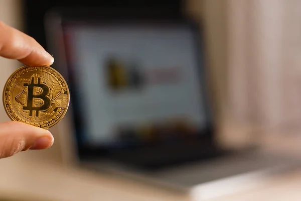 Bitcoin moeda de ouro na mão do homem no fundo do la — Fotografia de Stock