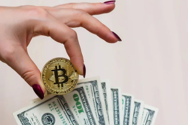 Bitcoin de oro en la mano de las mujeres en borrosa nosotros billetes de dólar b — Foto de Stock