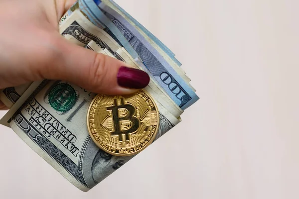 Bitcoin de oro en la mano de las mujeres en borrosa nosotros billetes de dólar b — Foto de Stock