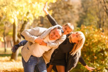 Sonbahar parkında çocuklu yürüyen bir aile 