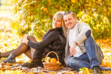 Romantik genç çift sonbahar sezonunda şehir parkında piknik yapar.