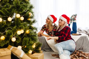 Noel eşyalarıyla süslü odada poz veren kız kardeşler. 