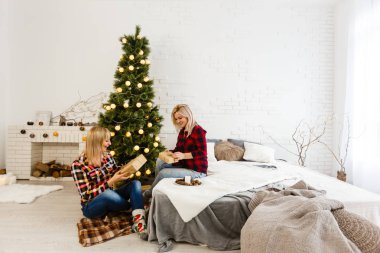 Noel eşyalarıyla süslü odada poz veren kız kardeşler. 