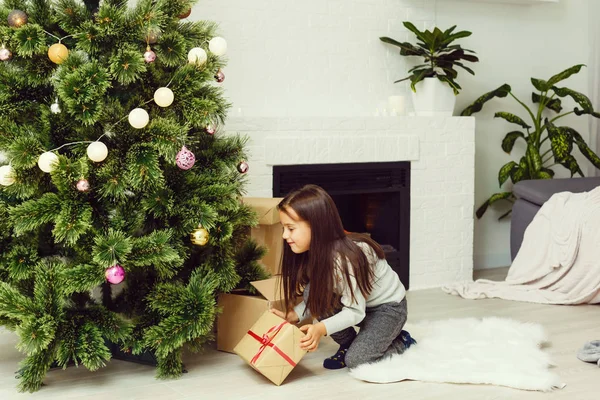 Menina sorrindo, colocando presentes de Natal sob o tre de Natal — Fotografia de Stock