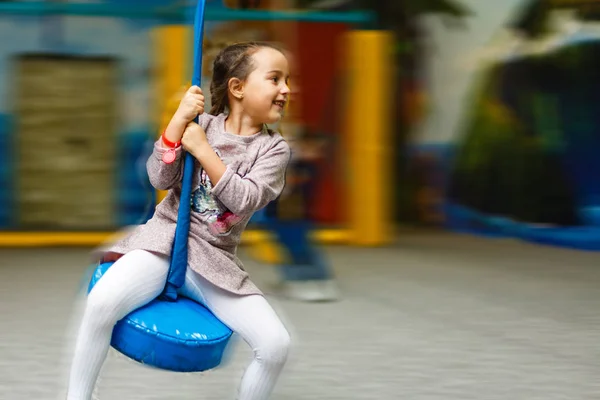 Słodka dziewczynka bawi się na placu zabaw. Dziewczyna jeździ konno. — Zdjęcie stockowe