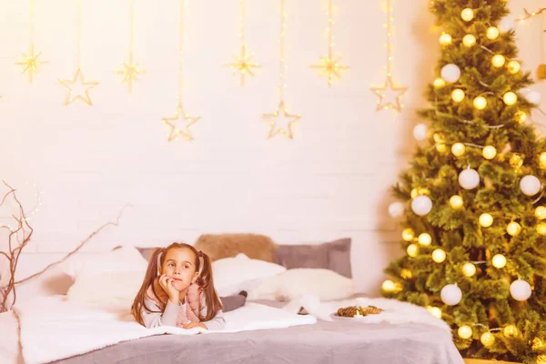 Kleines Mädchen Liegt Auf Einem Bett Einem Weihnachtlich Dekorierten Zimmer — Stockfoto