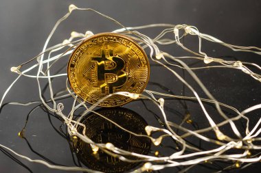 Altın bitcoin ve Noel süsleri ve ışıklar ile arkada başka bir bitcoin