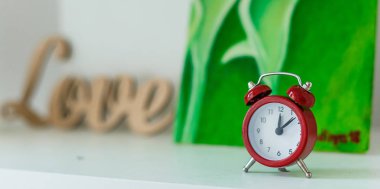 Ahşap masada eski usul kırmızı alarm saati. Çalar saat 8 'i gösteriyor.