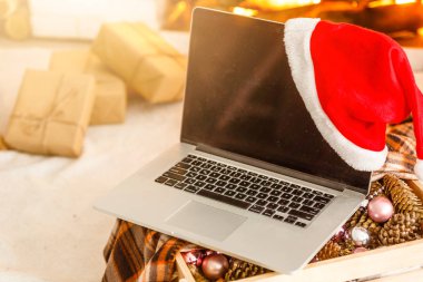 Boş ekranlı dizüstü bilgisayar, bulanık Noel ağacı ve arka planda hediyeler