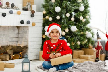 Küçük çocuk Noel ağacının yanında.