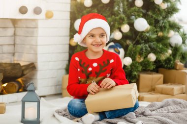 Küçük çocuk Noel ağacının yanında.