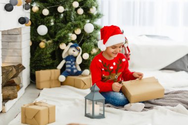 Küçük çocuk Noel ağacının yanında.