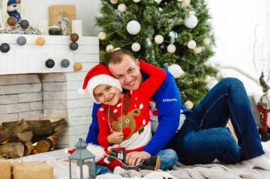 Gülümseyen baba ve oğlu evde Noel tatilinin tadını çıkarıyorlar.