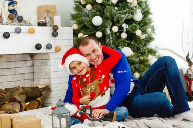 Gülümseyen baba ve oğlu evde Noel tatilinin tadını çıkarıyorlar.