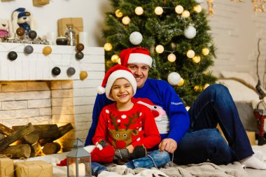 Gülümseyen baba ve oğlu evde Noel tatilinin tadını çıkarıyorlar.