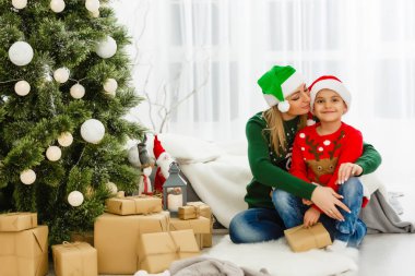 Genç anne ve tatlı oğlu Noel ağacının yanında hediyelerle oturuyorlar. 