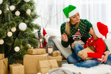 Genç anne ve tatlı oğlu Noel ağacının yanında hediyelerle oturuyorlar. 