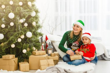 Genç anne ve tatlı oğlu Noel ağacının yanında hediyelerle oturuyorlar. 